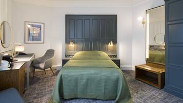 Una habitación de hotel con una cama, un escritorio con una silla, una mesita y un espejo.