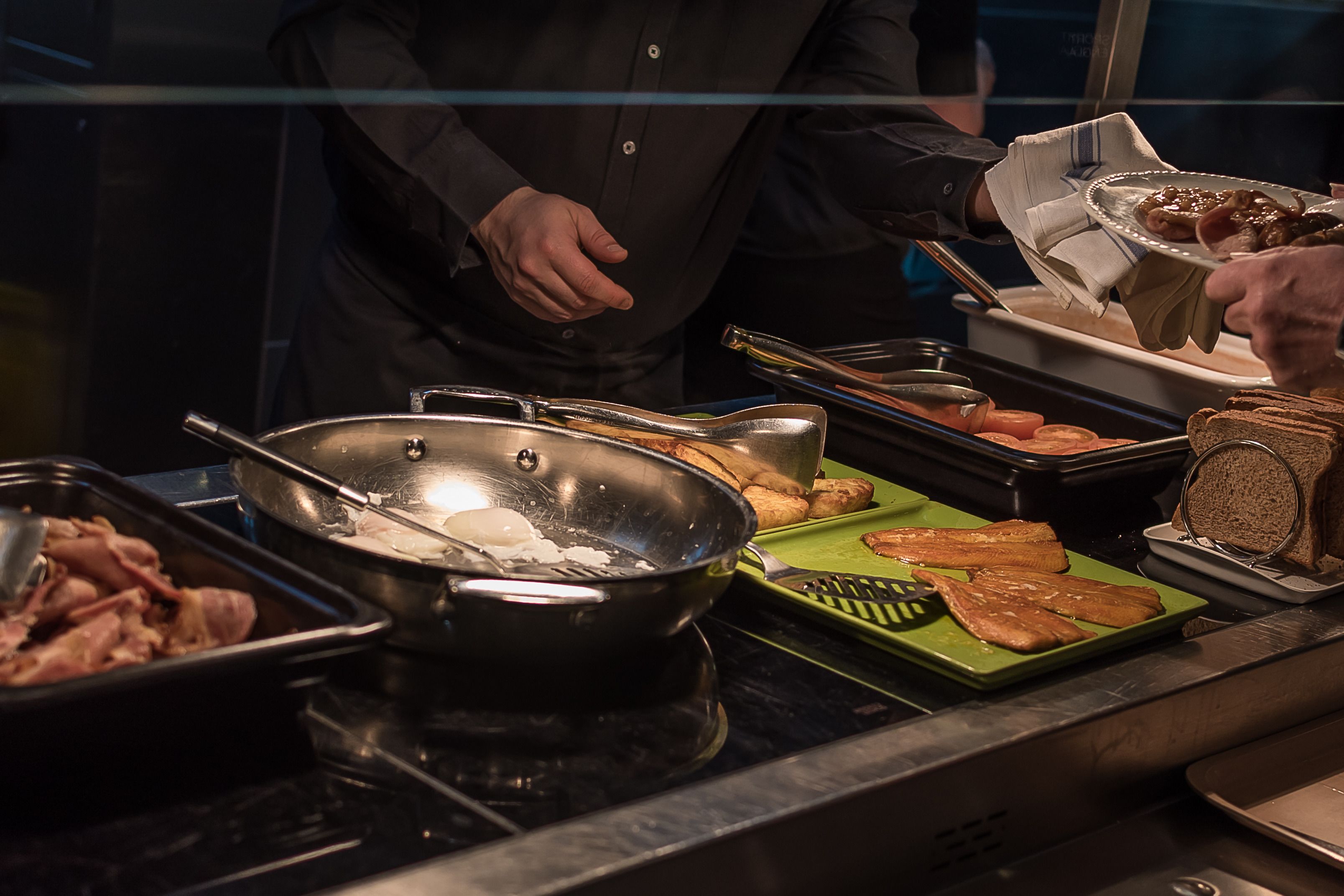 A buffet setup with various food items including meats, bread, and vegetables.