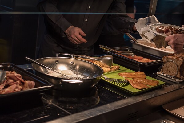 A buffet setup with various food items including meats, bread, and vegetables.