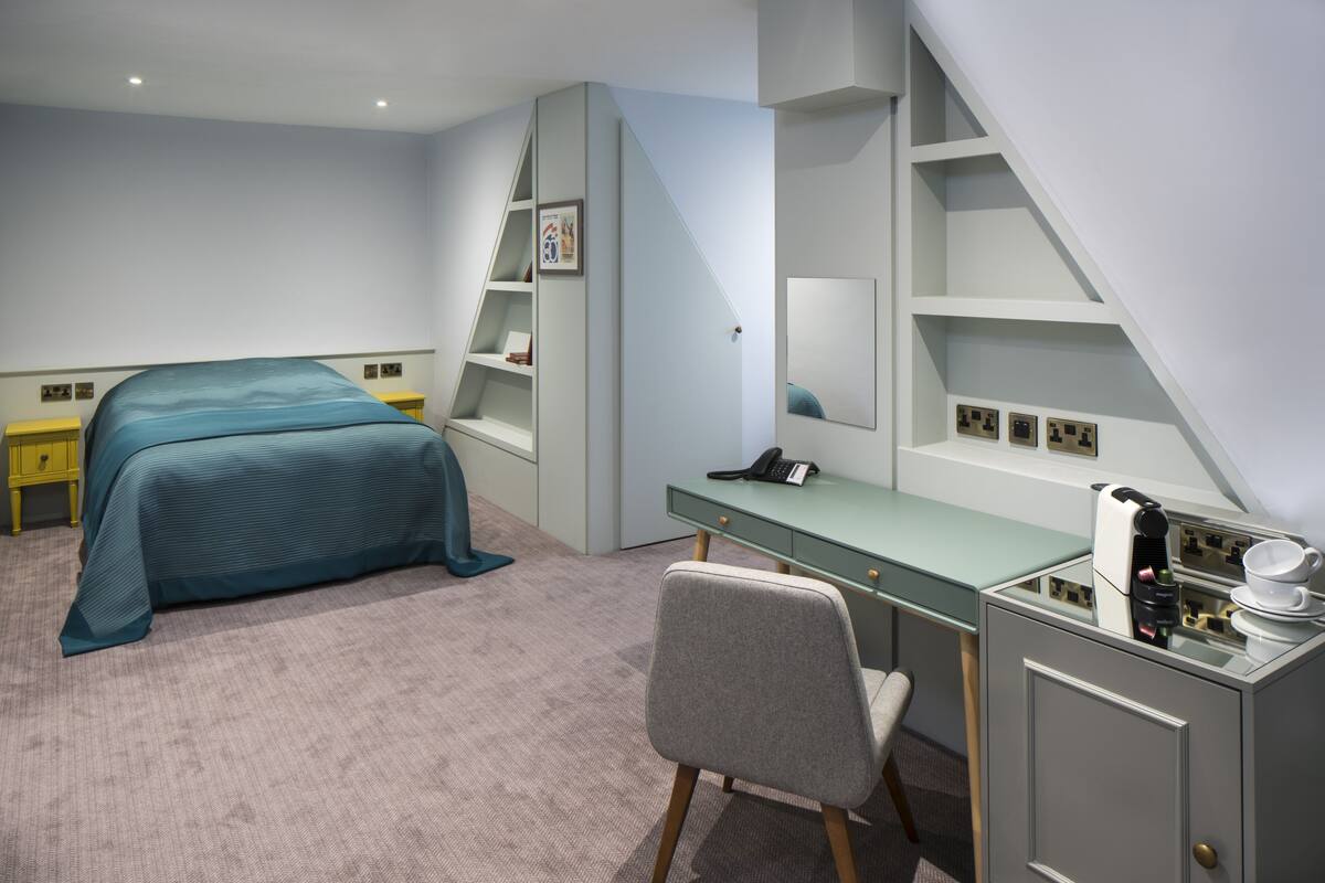 A bedroom with a bed, desk, chair, and built-in shelves.