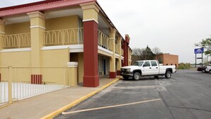 A hotel with a yellow facade, red accents, and a white pickup truck parked in front.