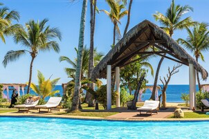 Una piscina al aire libre, sombrillas, sillones reclinables de piscina