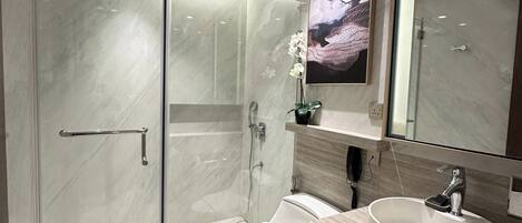 Une salle de bain moderne avec une douche à parois de verre, des toilettes, un lavabo et un grand miroir.