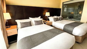 A hotel room with two beds, a large mirror, and a nightstand with a lamp.