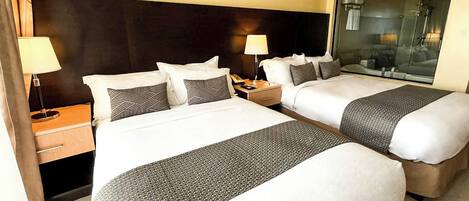 A hotel room with two beds, a large mirror, and a nightstand with a lamp.