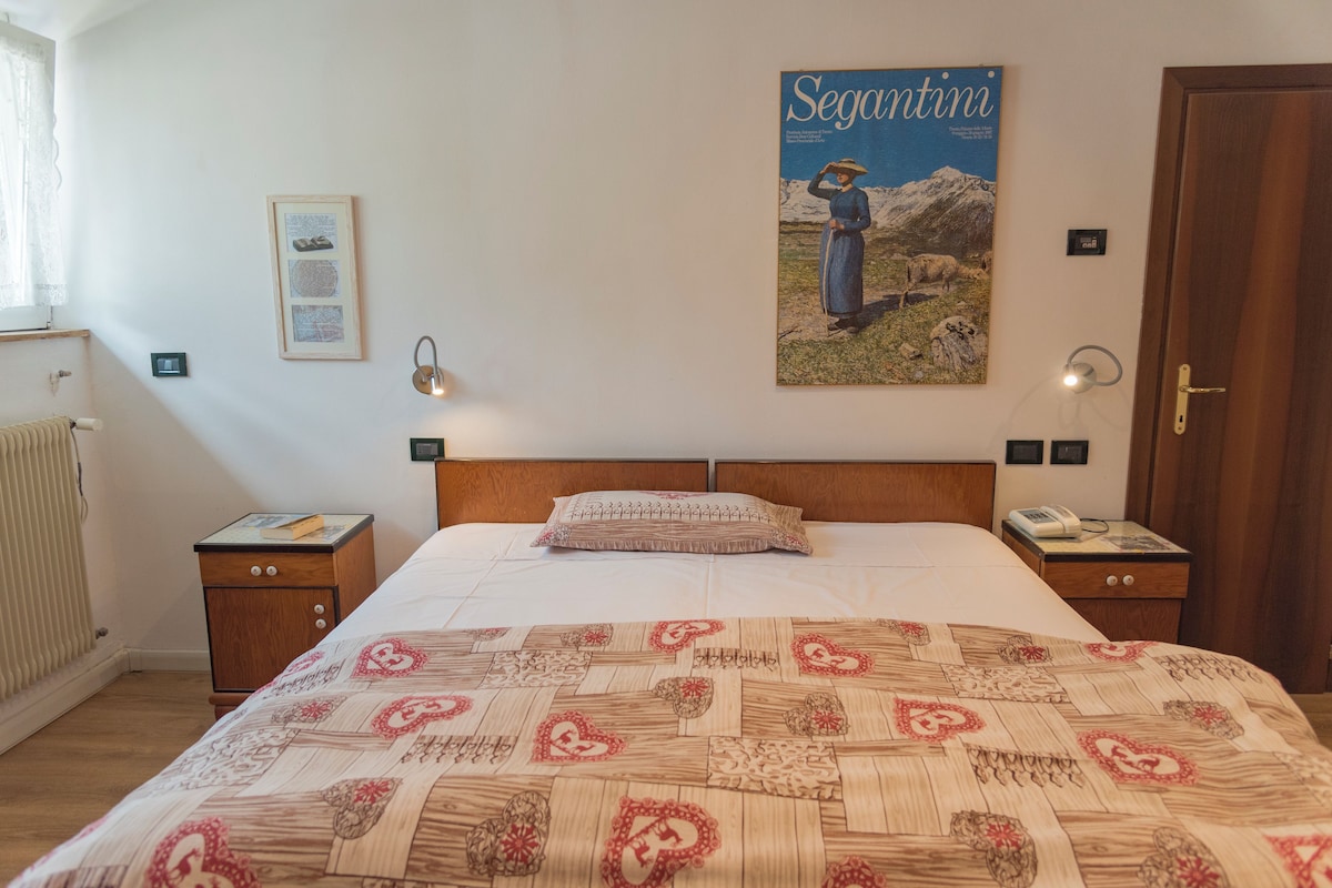 A bedroom with a large bed, a wooden headboard, a poster on the wall, and two bedside tables with lamps.