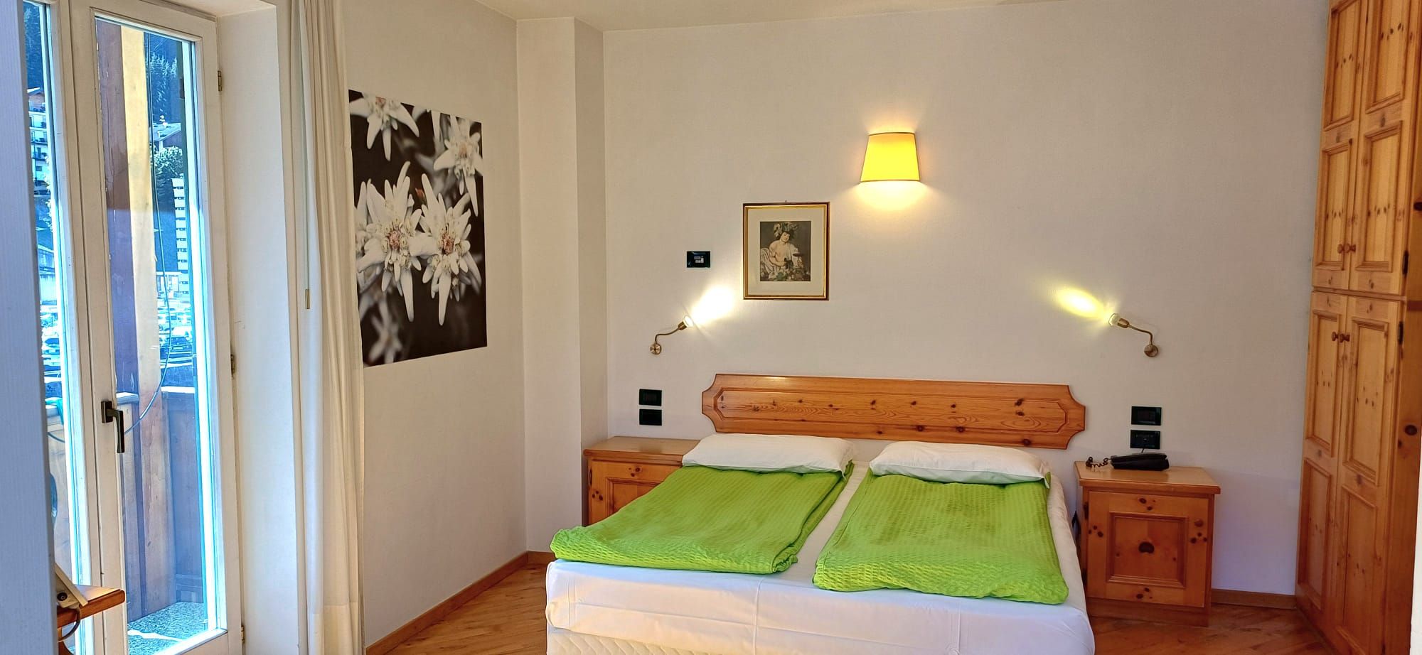 Una camera da letto con un letto in legno, due comodini, una lampada a parete e un quadro incorniciato.