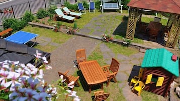Relax in the serene outdoor patio area, featuring a ping pong table, dining table, lounge chairs, and a charming garden.