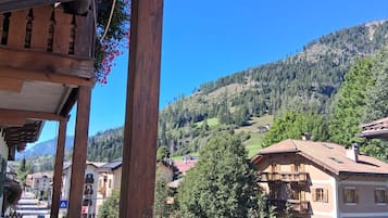 A wooden balcony with a view of a hillside village and a clear blue sky.