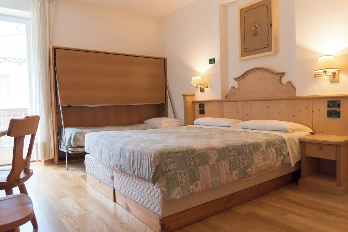 Ein Doppelbett mit Patchworkdecke, Nachttischlampen, einem Holz-Kopfteil und einem kleinen Nachttisch.