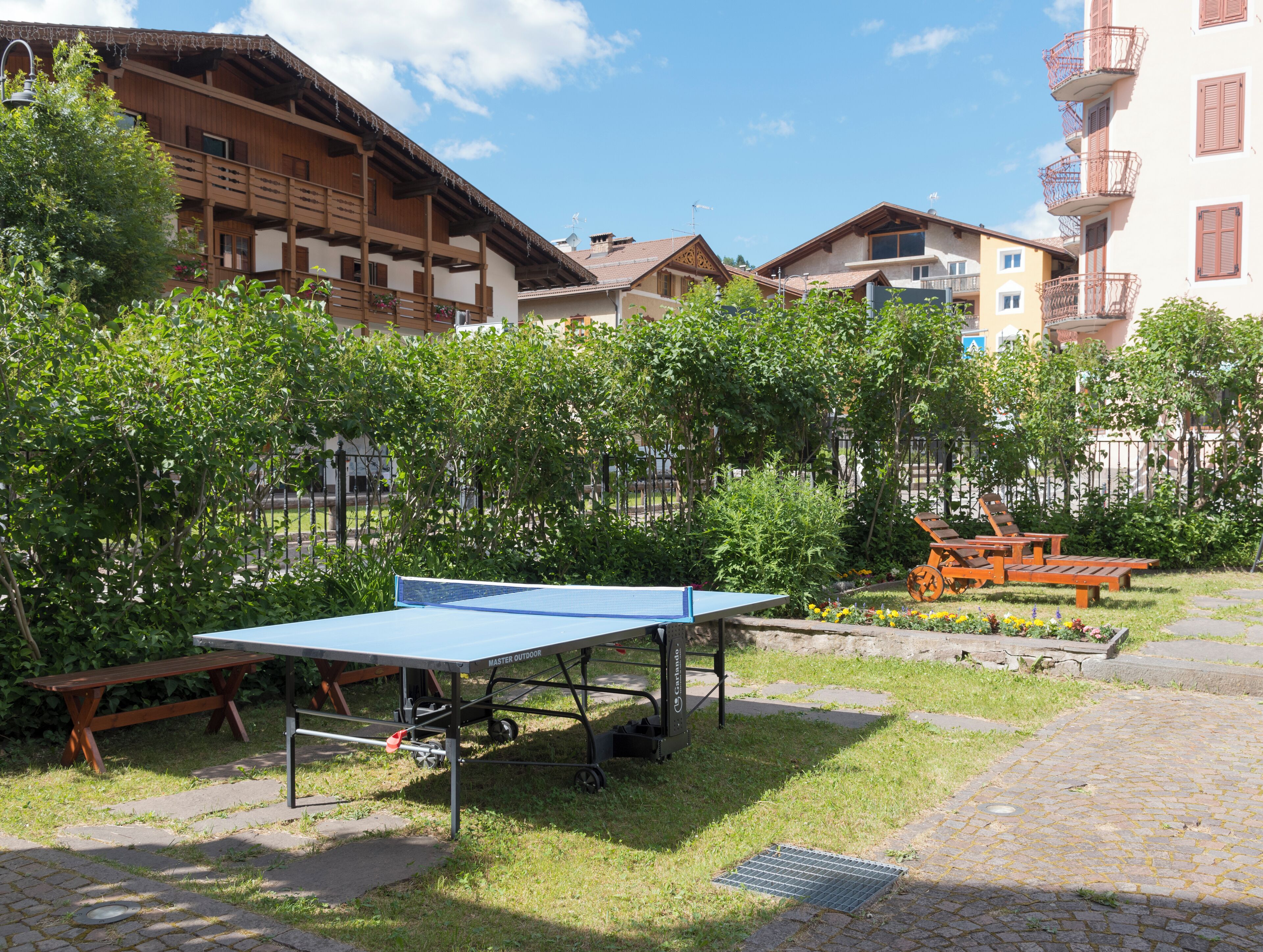 Un cortile con un tavolo da ping pong, panchine e un'area giardino.