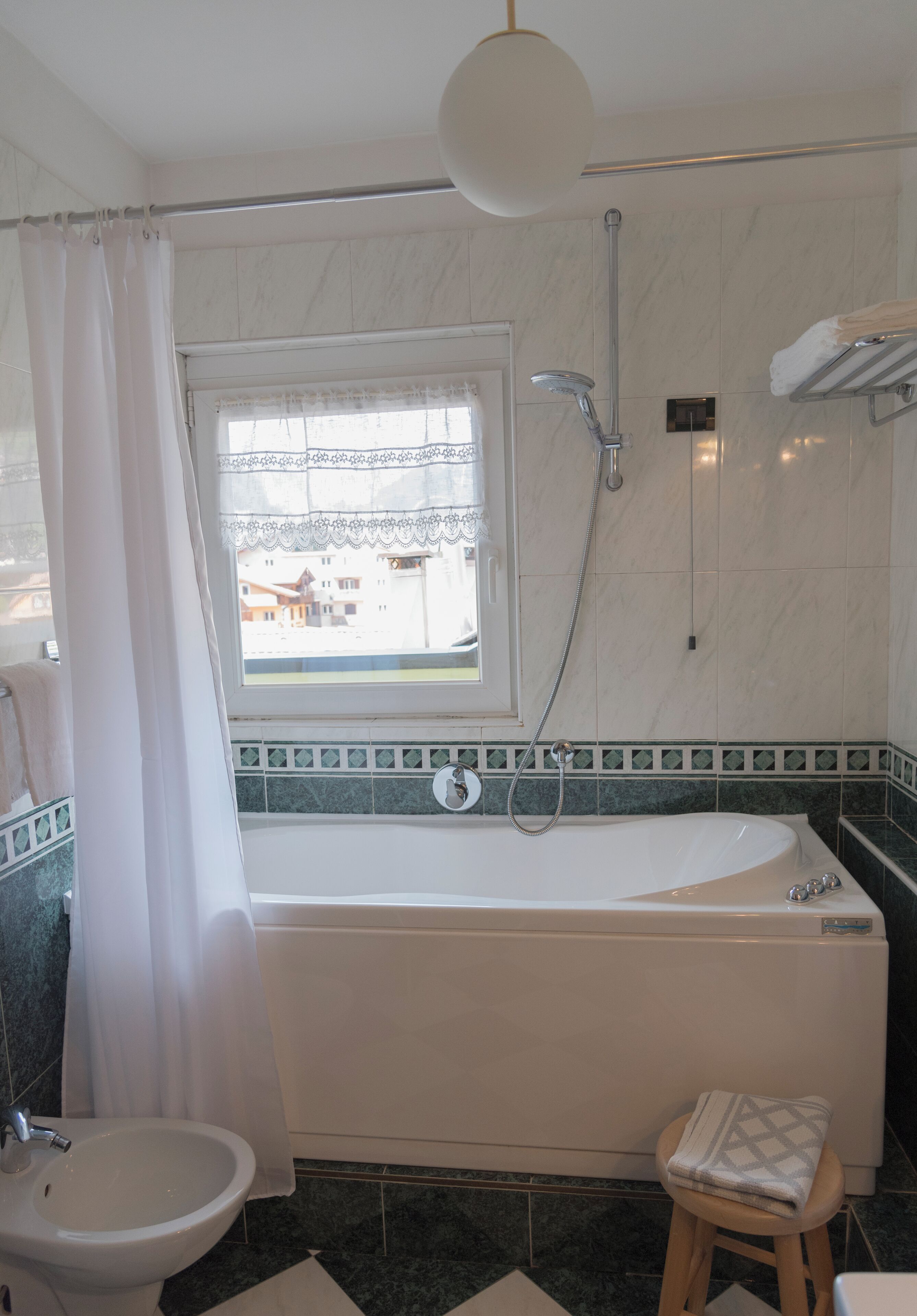 A bathroom with a bathtub, a window, a shower, and a toilet.