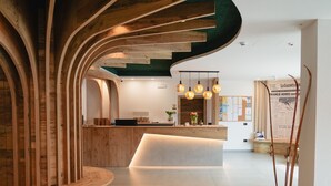 Una moderna zona de recepción con un mostrador de madera, una escalera curva e iluminación colgante.