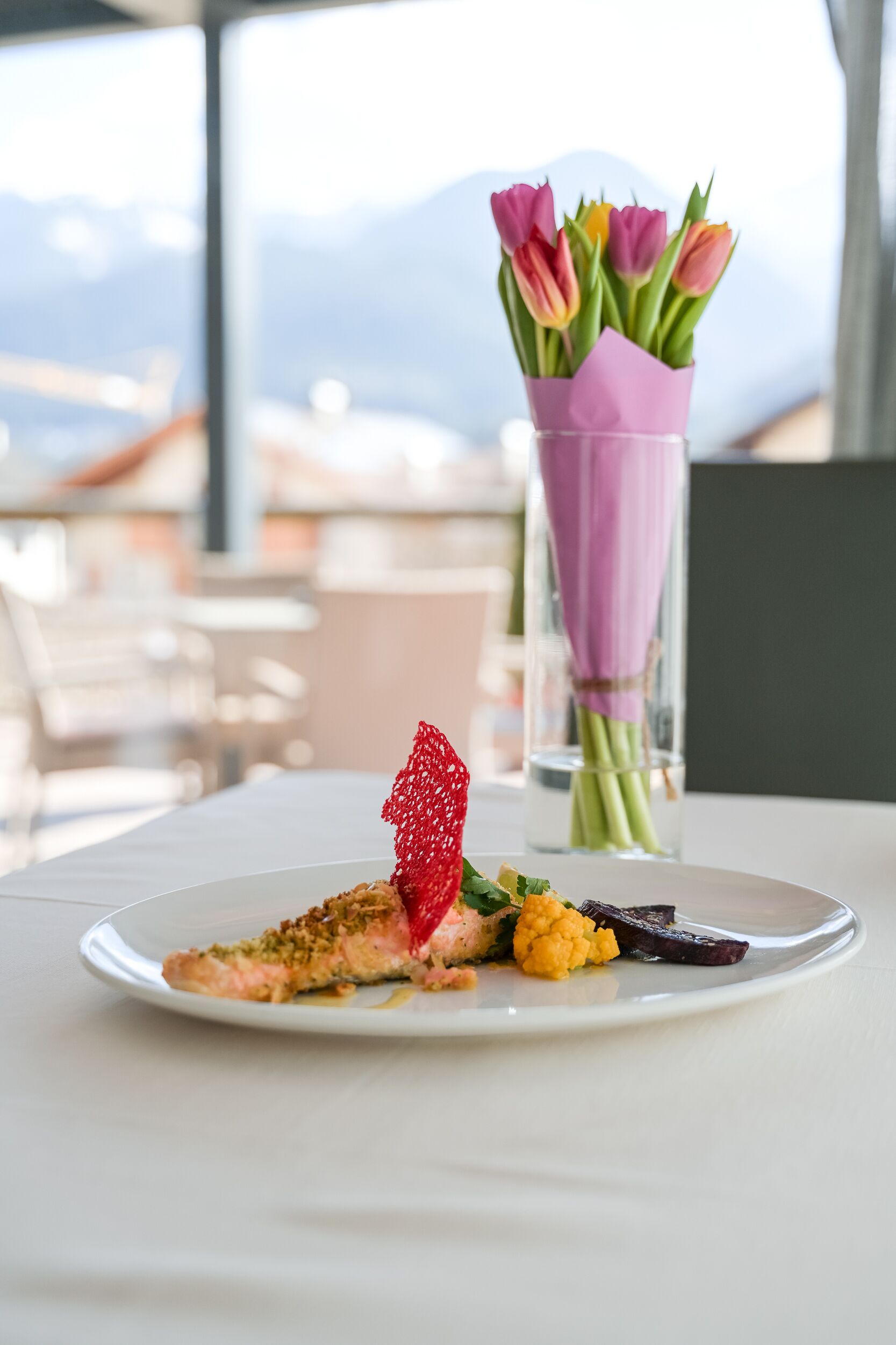 A plate of food with a decorative element and a vase of flowers on a table.
