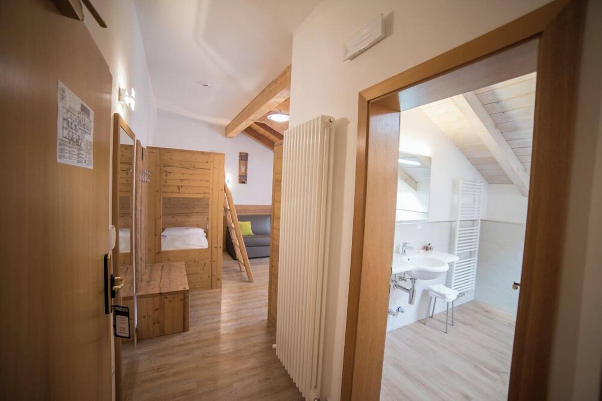 A narrow hallway leading to a bedroom with a wooden bunk bed, a small table, and a chair.