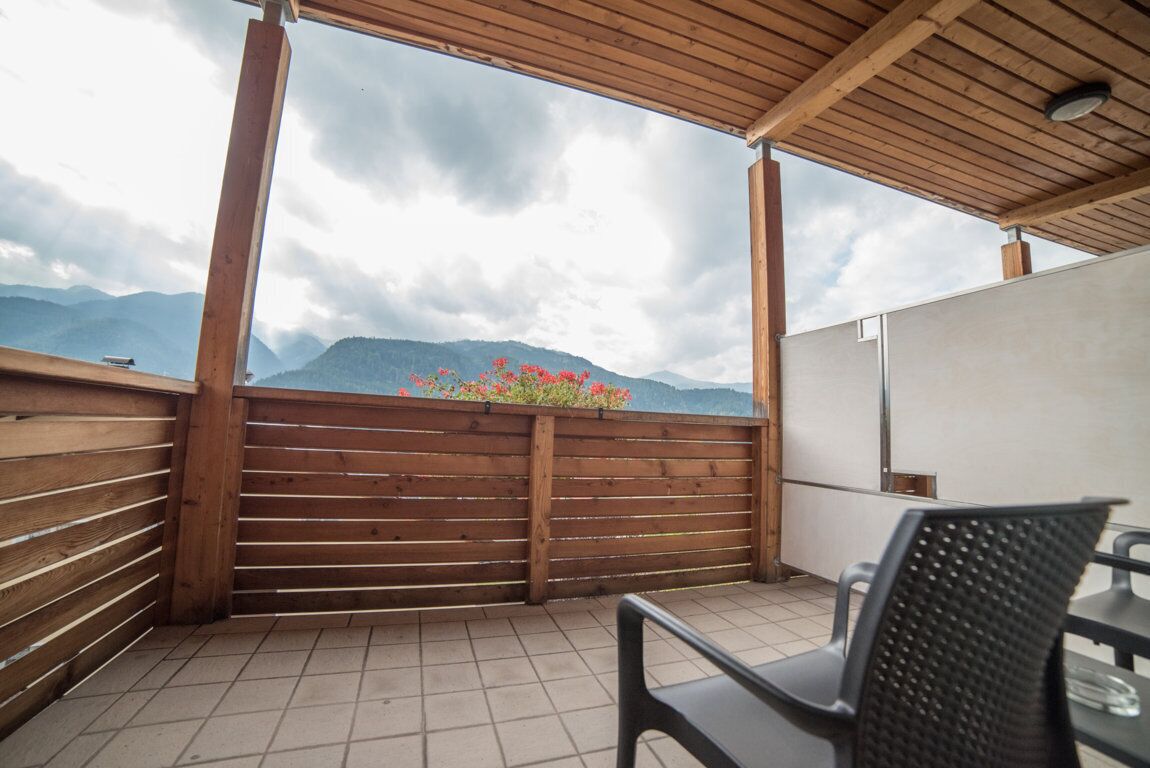 Ein Balkon mit Holzbalkonen, Fliesenboden und einem Stuhl.