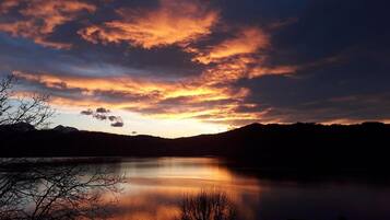 A serene lake at sunset with a silhouette of mountains in the background.