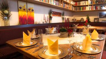 Un restaurante con una larga mesa de madera dispuesta para una comida, rodeado de estanterías llenas de libros.