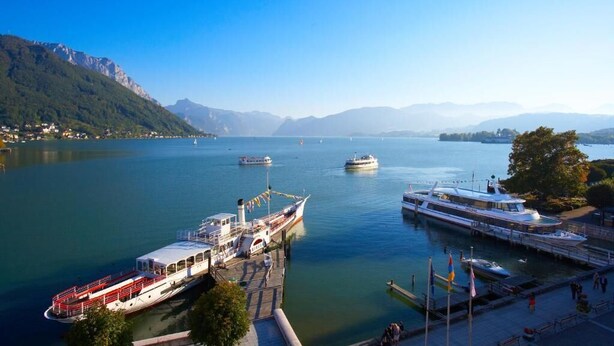 A marina with several boats docked, surrounded by mountains and clear skies. - Landhotel Gasthof Grunberg (Gmunden)