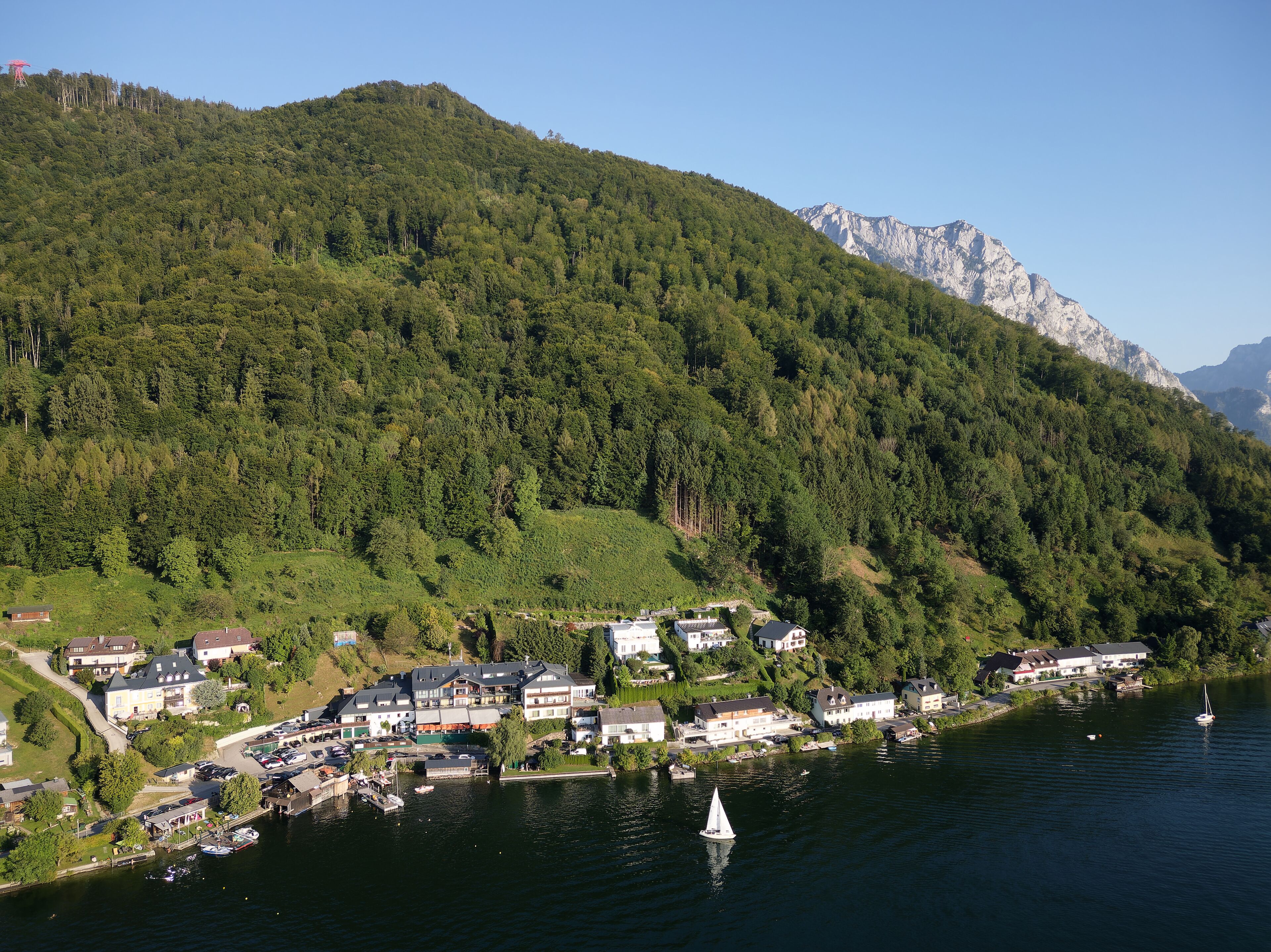 A lakeside village with houses and a sailboat on the water.
