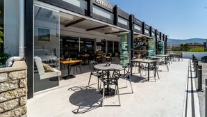 An outdoor seating area with tables and chairs, a glass storefront, and a sign that reads "terra cafe".
