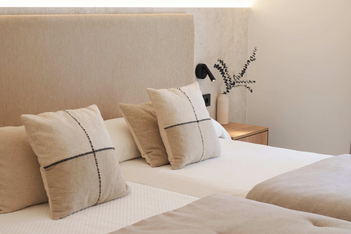 A bedroom with a large bed, two bedside tables, and a wall-mounted lamp.