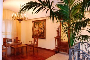 Una stanza con un tavolo da pranzo in legno, sedie, un lampadario, un quadro di grandi dimensioni e una pianta in vaso.