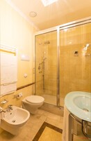 Un bagno con doccia vetro, lavandino bianco e bidet.