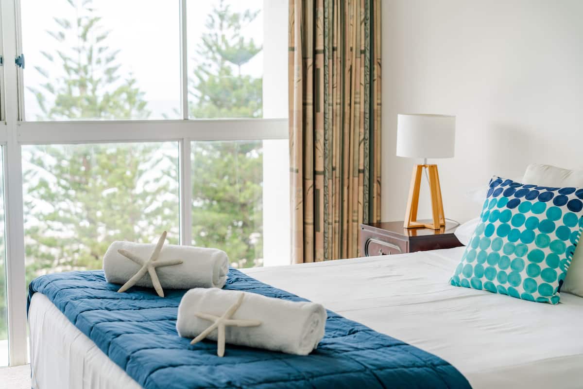 Una cama con colcha azul, una toalla blanca y una decoración con forma de estrella de mar.