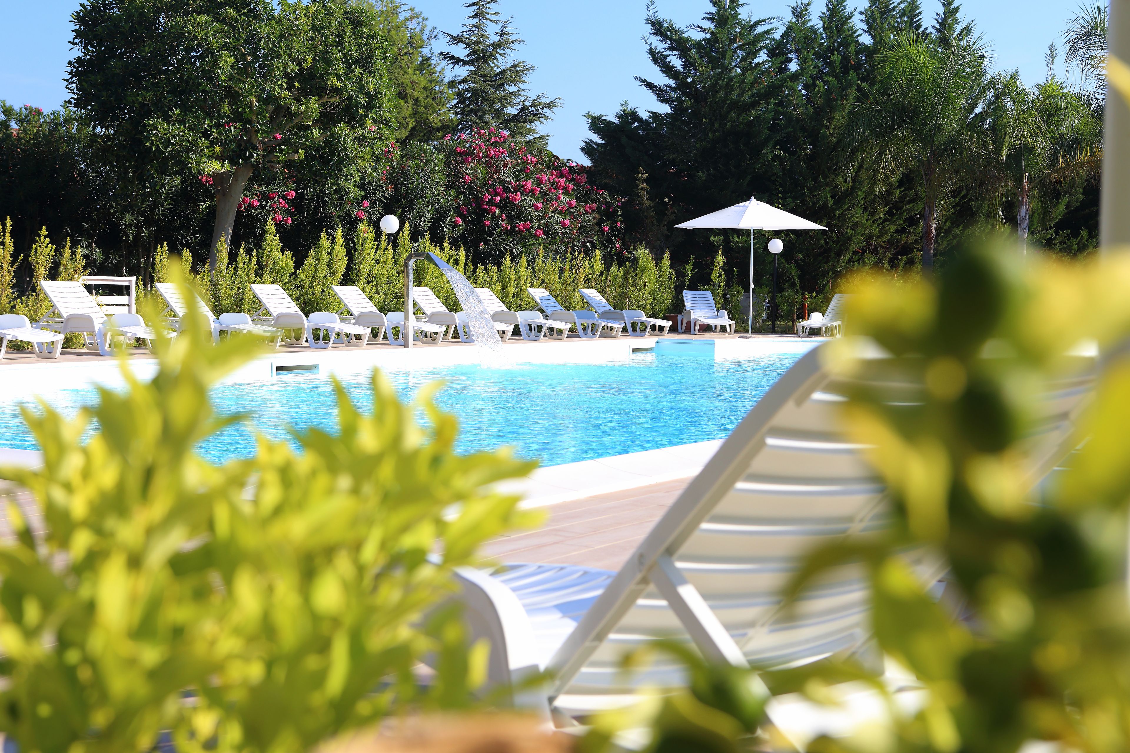 Area piscina con lettini e elemento d'acqua.