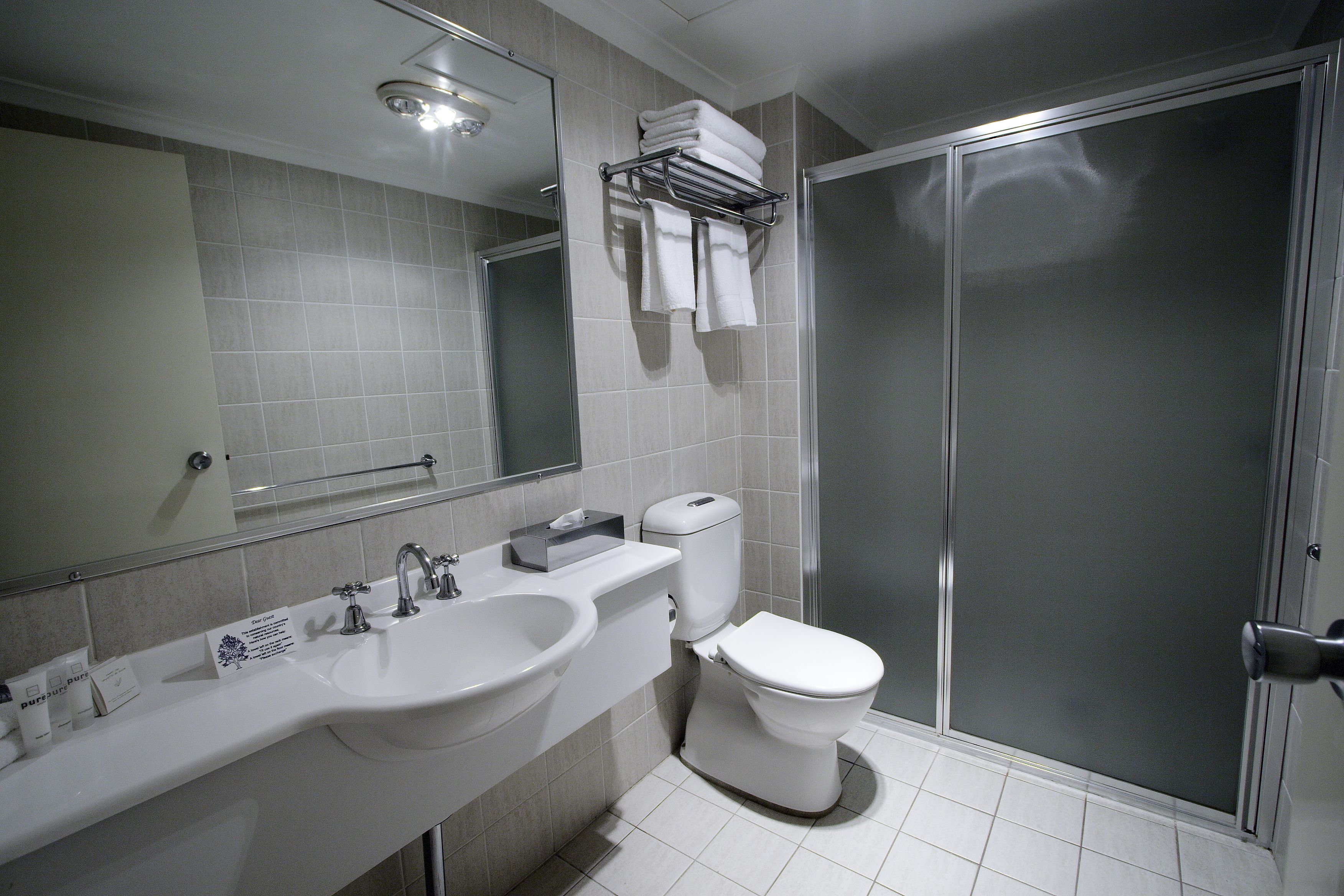 A modern bathroom with a sink, mirror, and toilet.