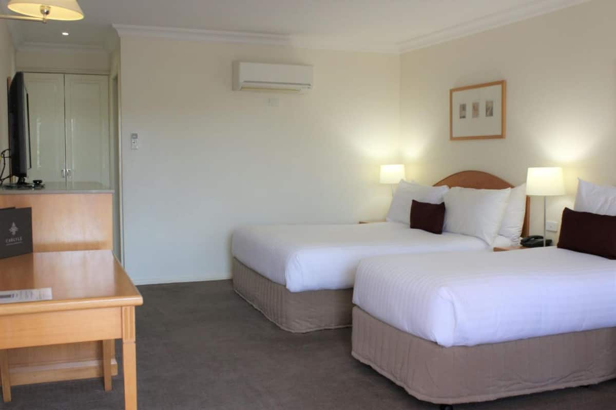 A hotel room with two beds, a desk, and a wardrobe.