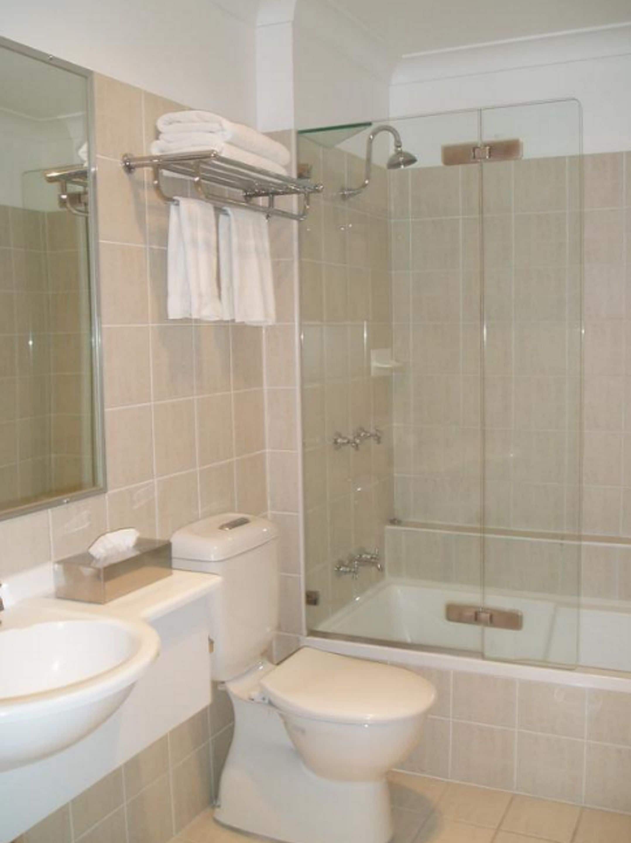 A bathroom with a toilet, sink, and glass-enclosed shower stall.