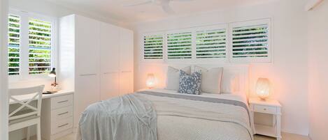 A bedroom with a bed, bedside tables, a desk, and a chair.