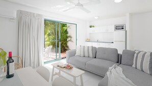 A modern living room with a grey sofa, a small white table, and a ceiling fan.