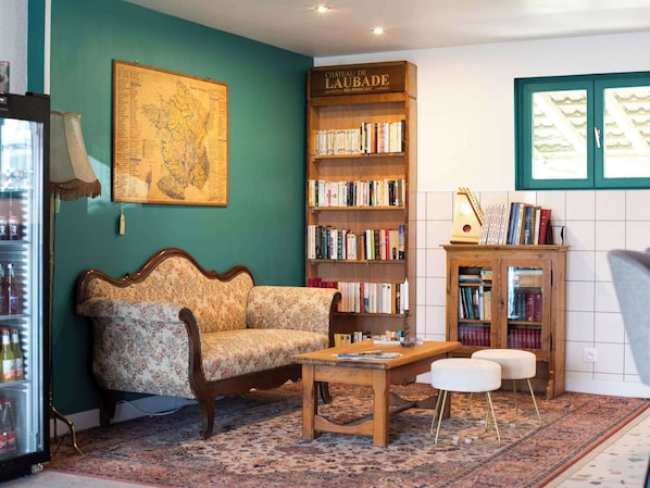 A cozy room with a sofa, a wooden bookshelf, a map on the wall, and a small table.