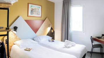 Quarto de hotel com duas camas, uma escrivaninha, uma cadeira, uma janela com cortinas e um quadro na parede.