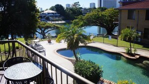 Zona de piscina con vistas al horizonte urbano, rodeada de árboles y una valla.