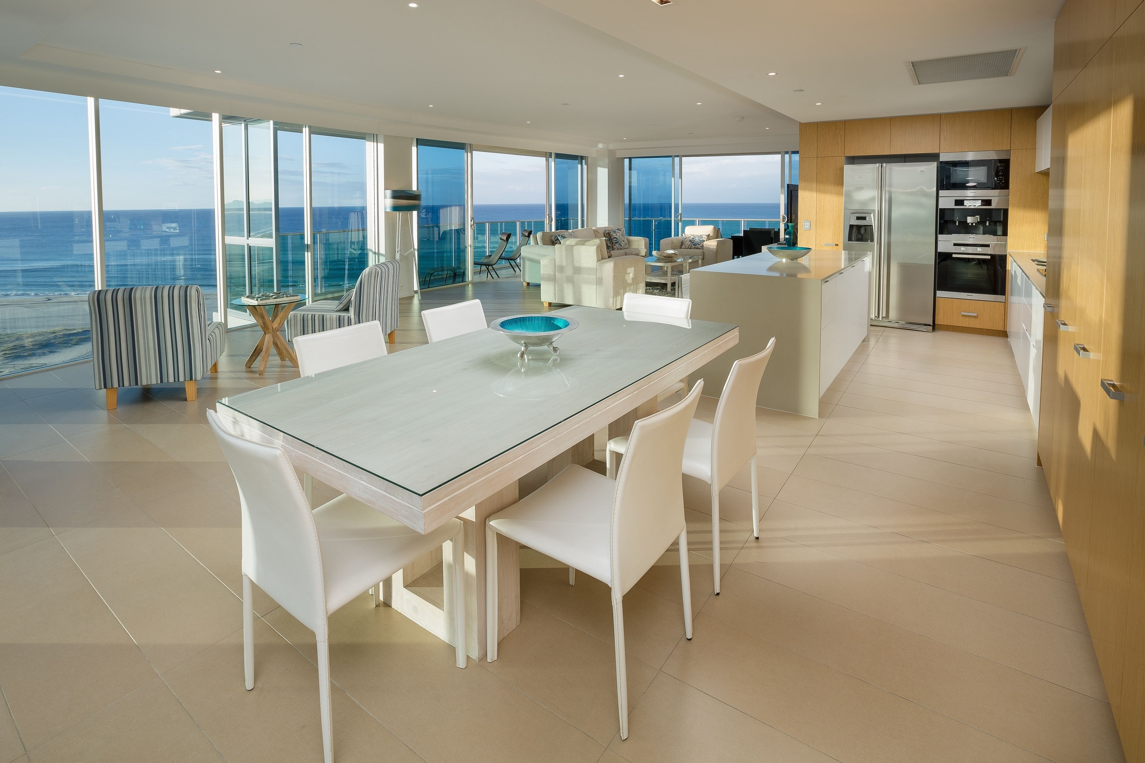 A modern kitchen with a large island, white cabinetry, and a view of the ocean.