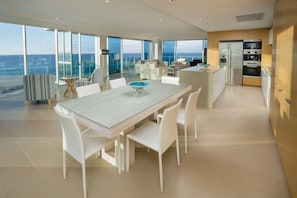 A modern kitchen with a large island, white cabinetry, and a view of the ocean.