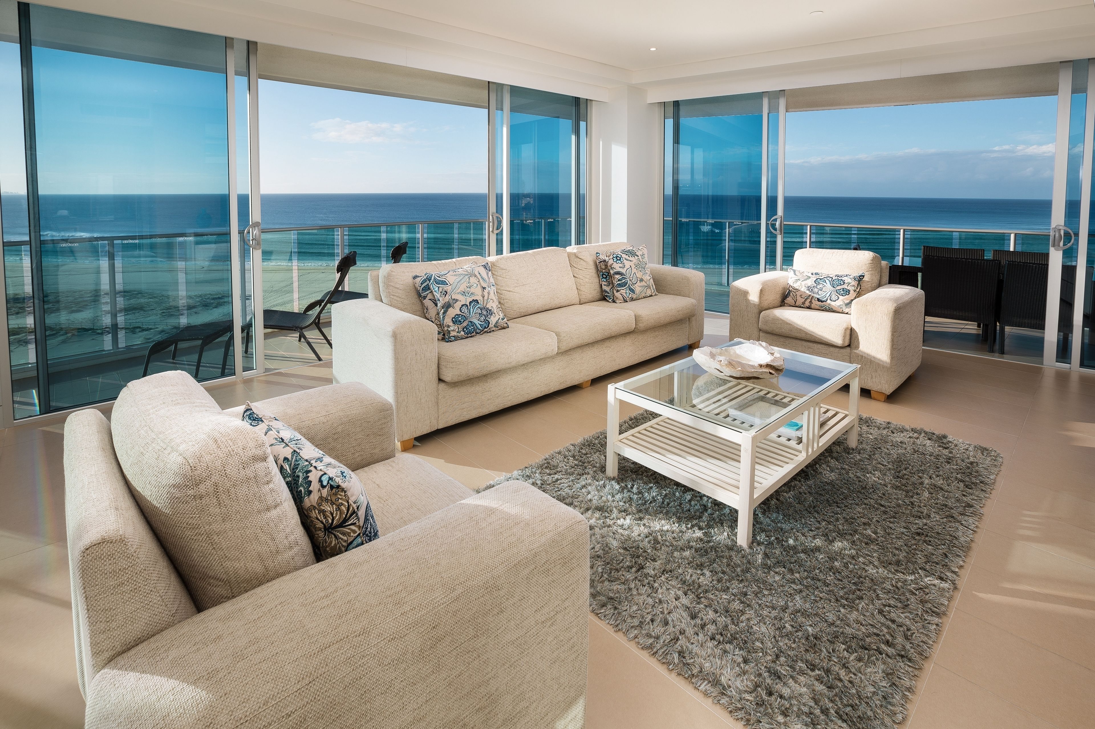 A modern living room with a large glass balcony overlooking the ocean.