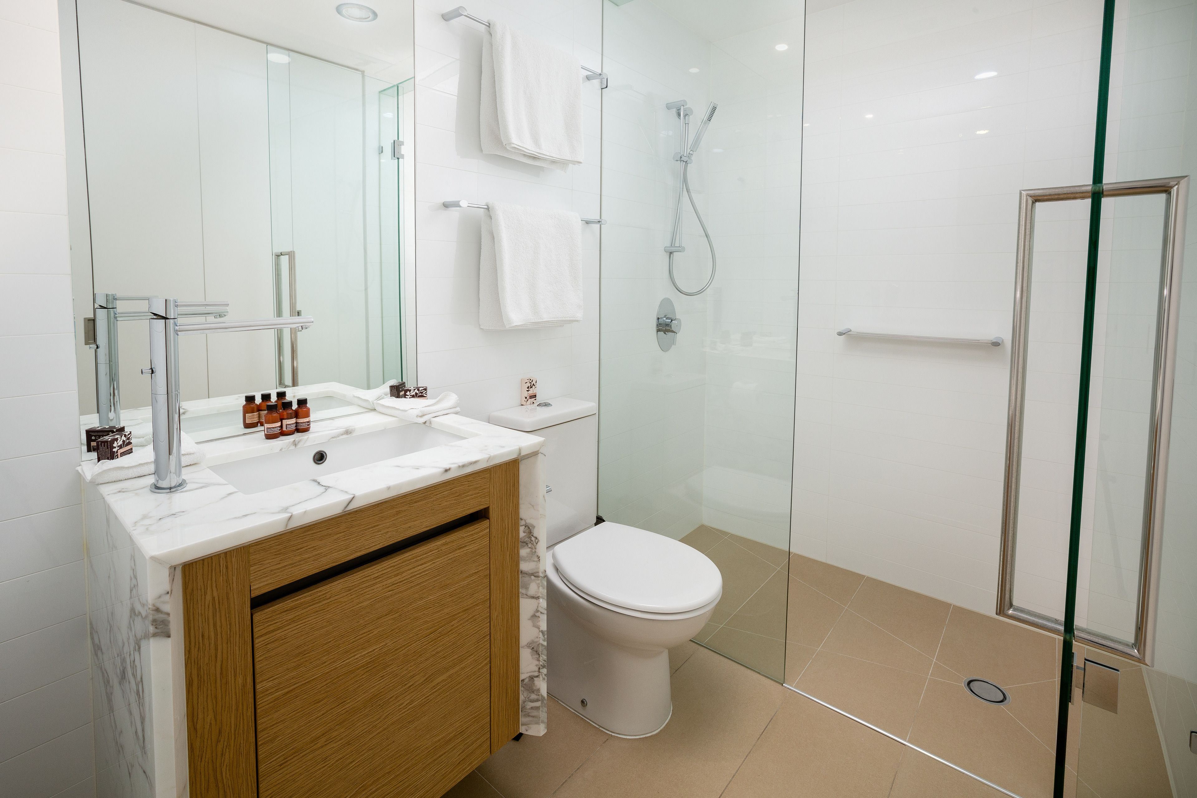 A modern bathroom with a glass-enclosed shower, a white toilet, and a marble vanity with a sink.