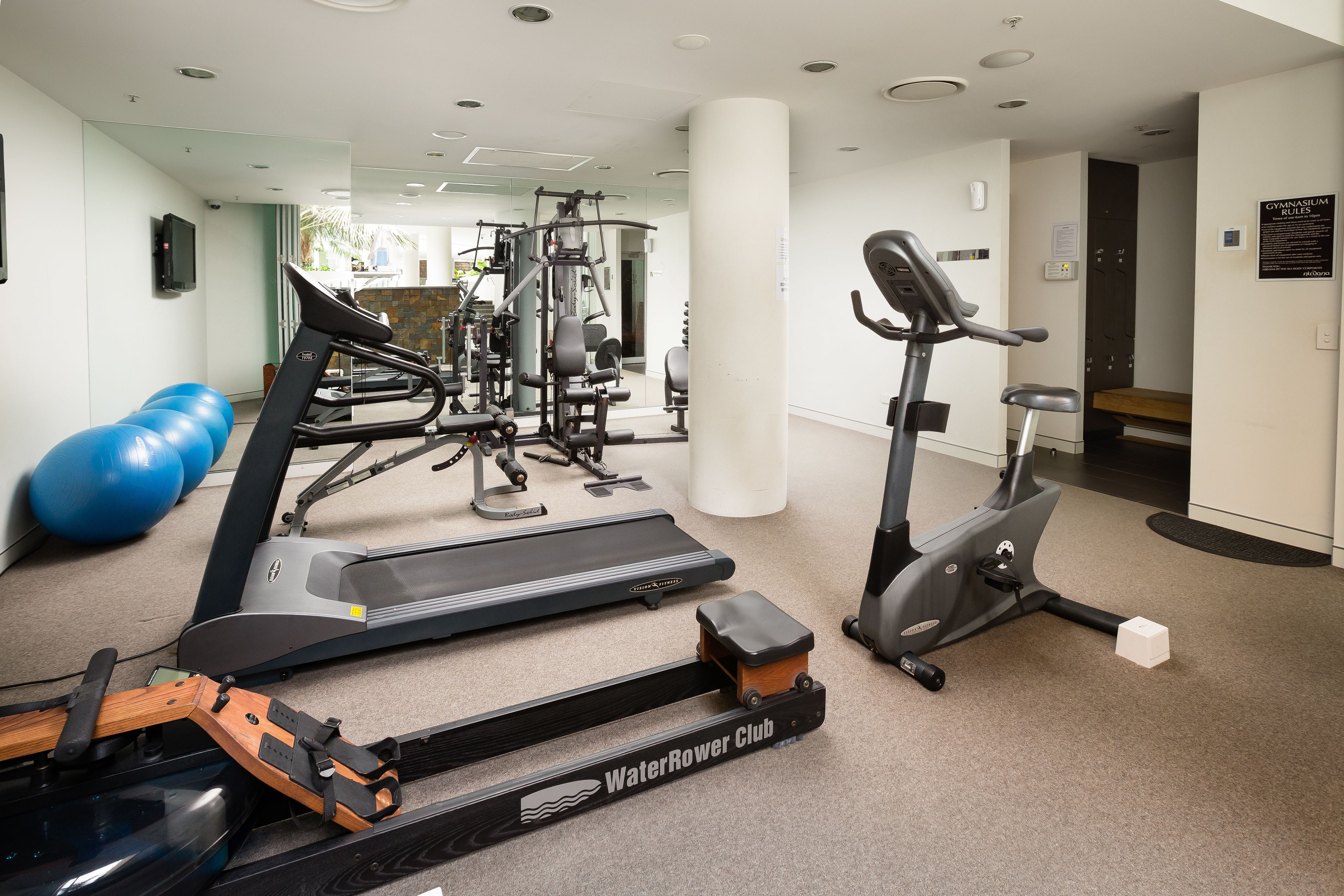 Une salle de sport équipée de machines de cardio, de matériel de musculation et de ballons d’exercice.