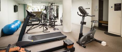 Une salle de sport équipée de machines de cardio, de matériel de musculation et de ballons d’exercice.