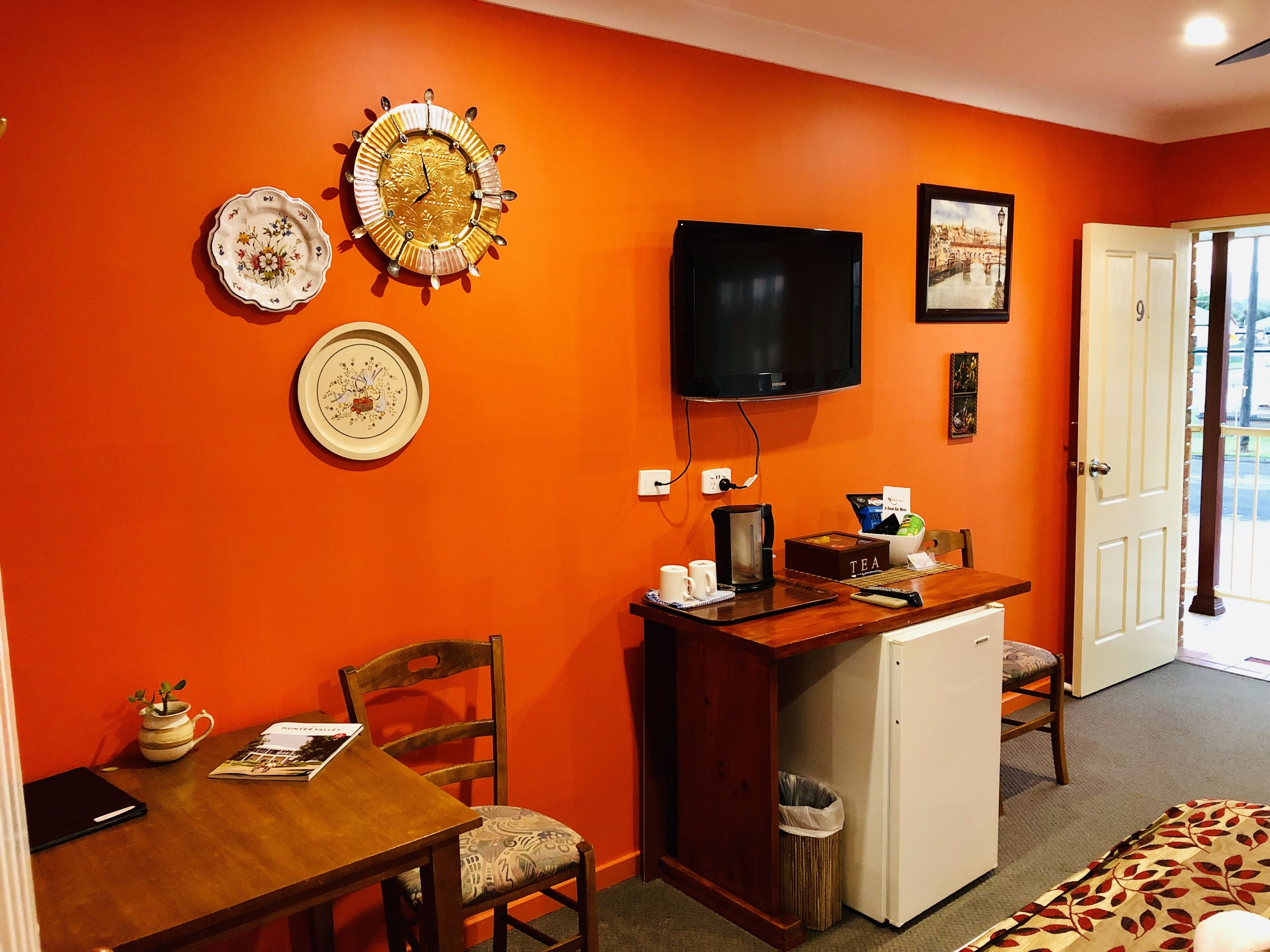 Um espaço compacto para relaxar, com cozinha compacta, área de refeições e televisão na parede.