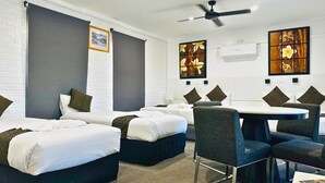 A hotel room with two beds, a dining table with chairs, and artwork on the walls. - Aussie Rest Motel (Cessnock)