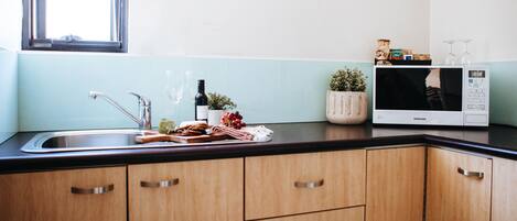 A kitchen with wooden cabinets, a stainless steel sink, a microwave, and a window.
