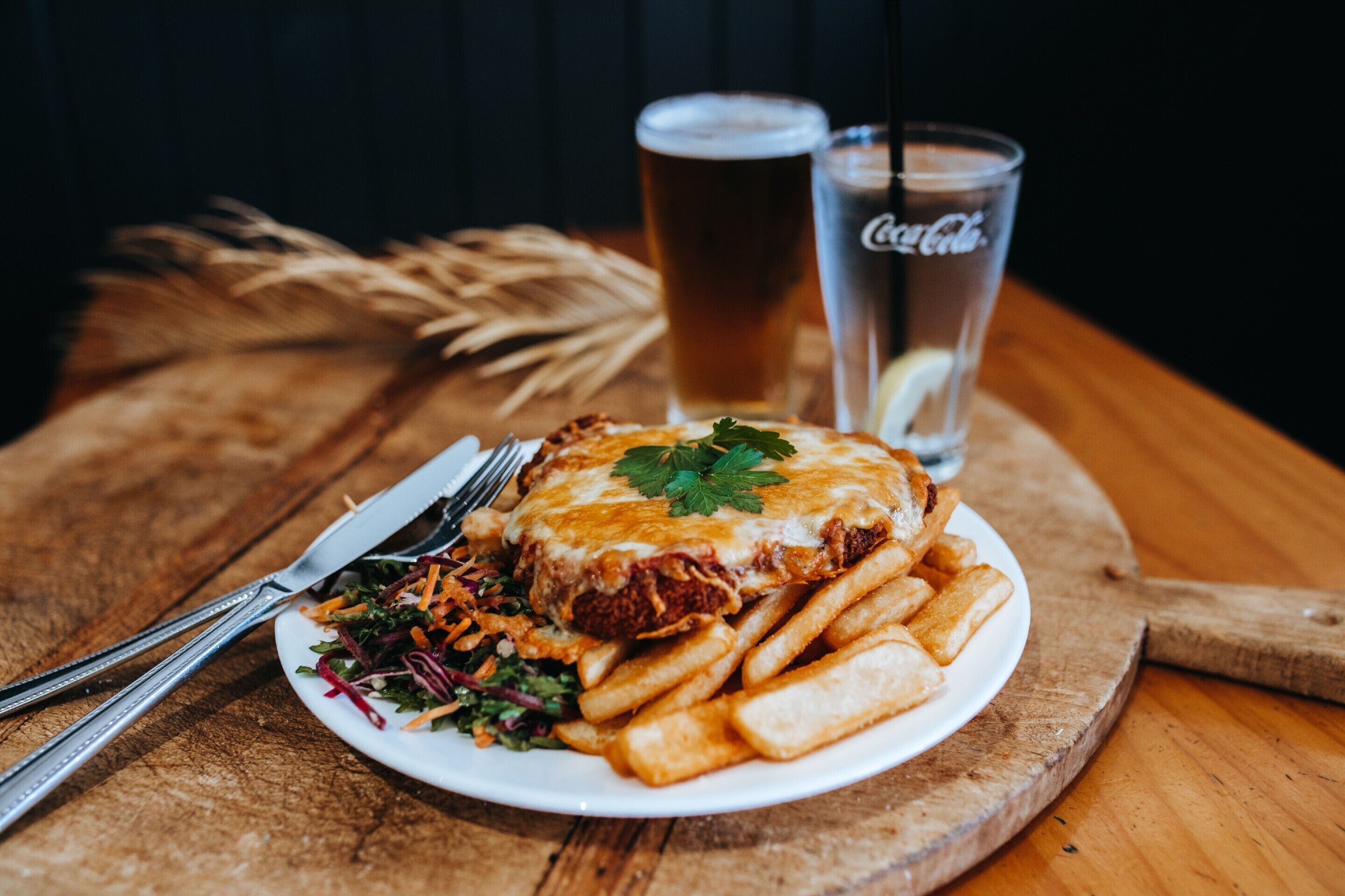 A plate of food with fries and a drink on a wooden table.