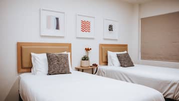 A hotel room with two beds, white bedding, wooden headboards, and framed artwork on the wall.