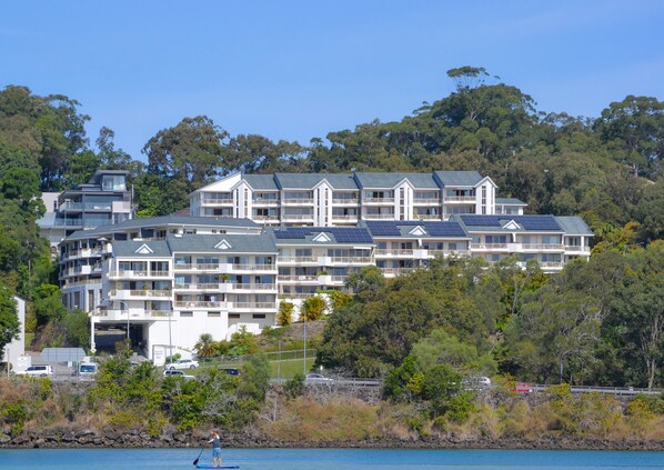 A multi-story hotel with balconies, solar panels, and a view of the surrounding forest. - The Hill Apartments (Currumbin)